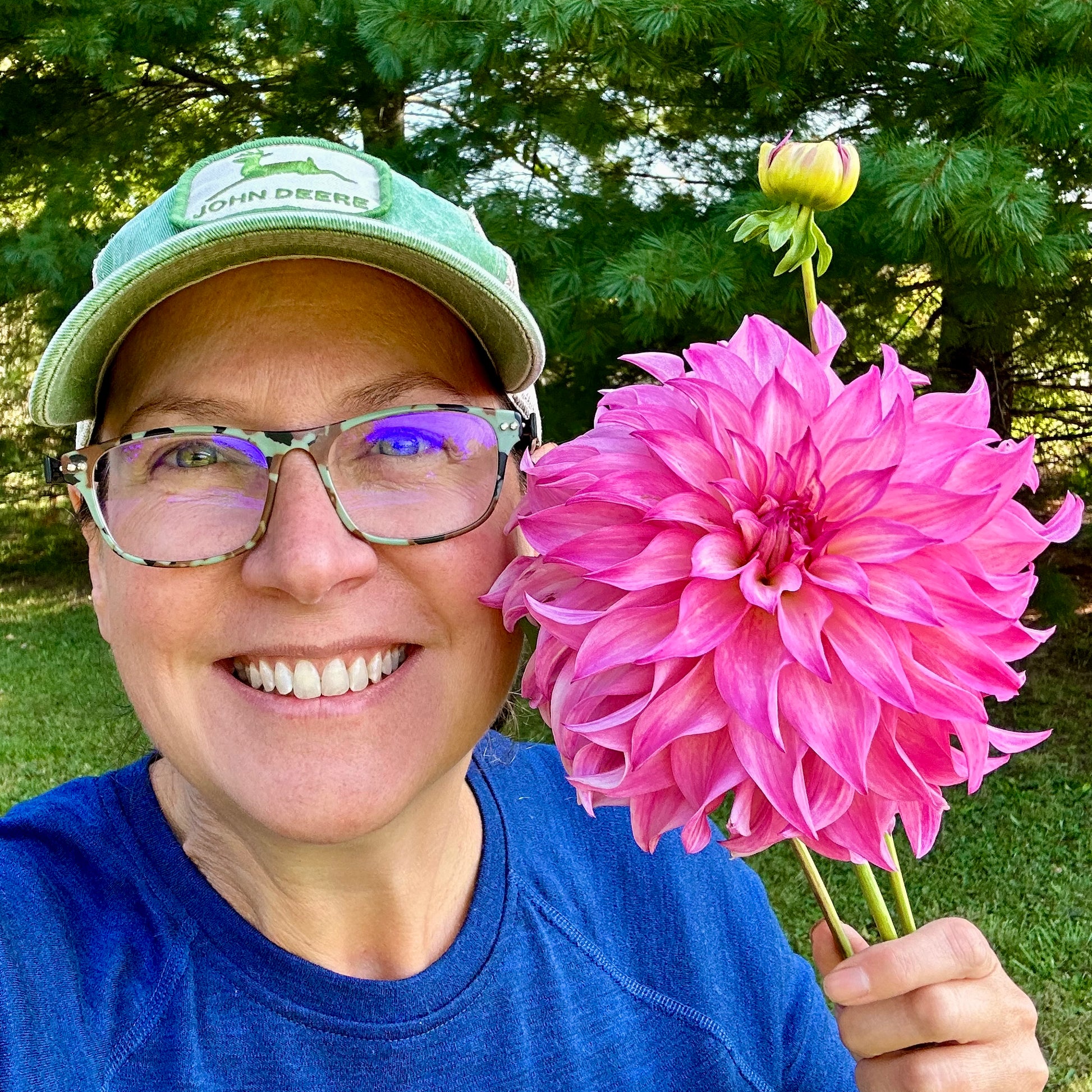 Brainy holding a freshly cut bloom of a Colorado Classic dahlia, which is as large as her face. 